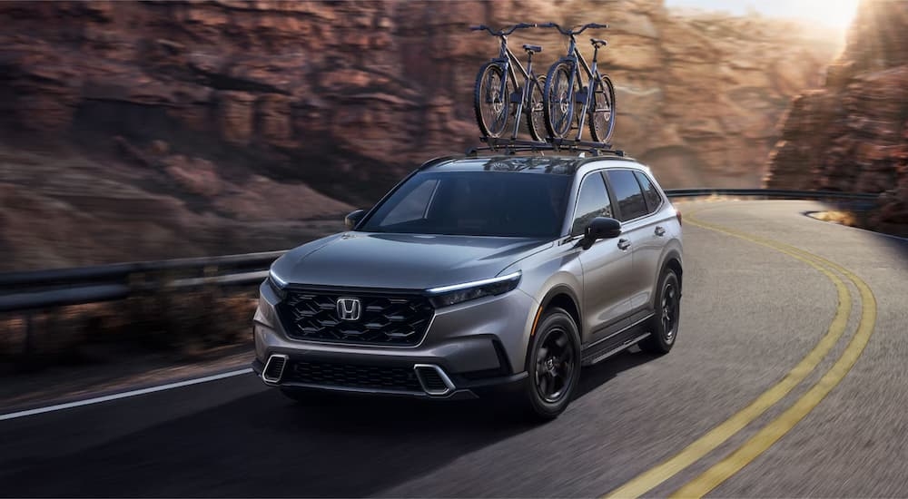 A grey 2025 Honda CR-V Sport Touring Hybrid driving through a canyon.