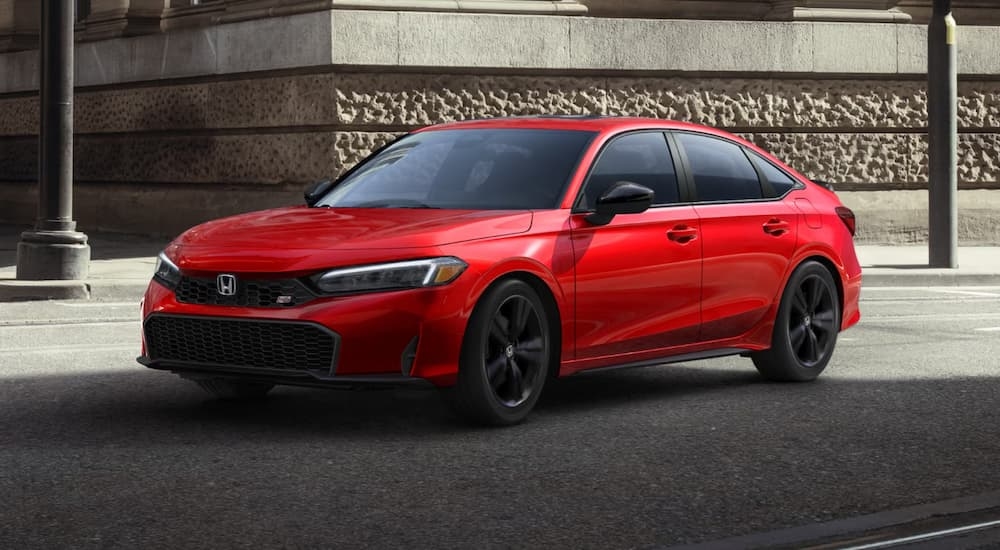 A red 2025 Honda Civic Si parked by a city curb.