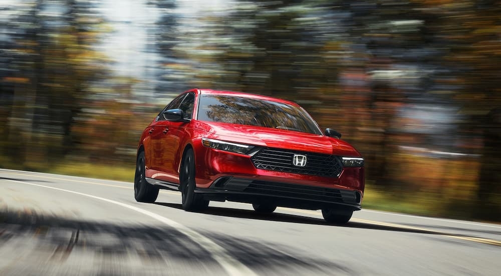 A red 2025 Honda Accord SE driving around a bend.