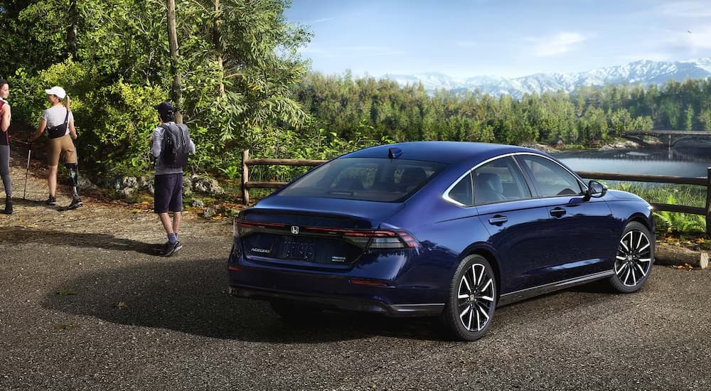 People walking from a blue 2025 Honda Accord SE parked by a forest.