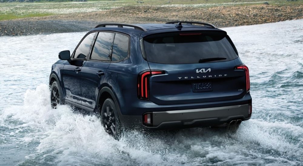 A dark blue 2025 Kia Telluride is shown driving through a creek.