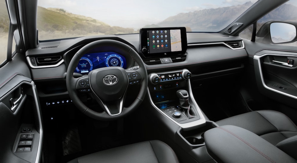 The steering wheel and dashboard in the black interior of a 2025 Toyota RAV4.