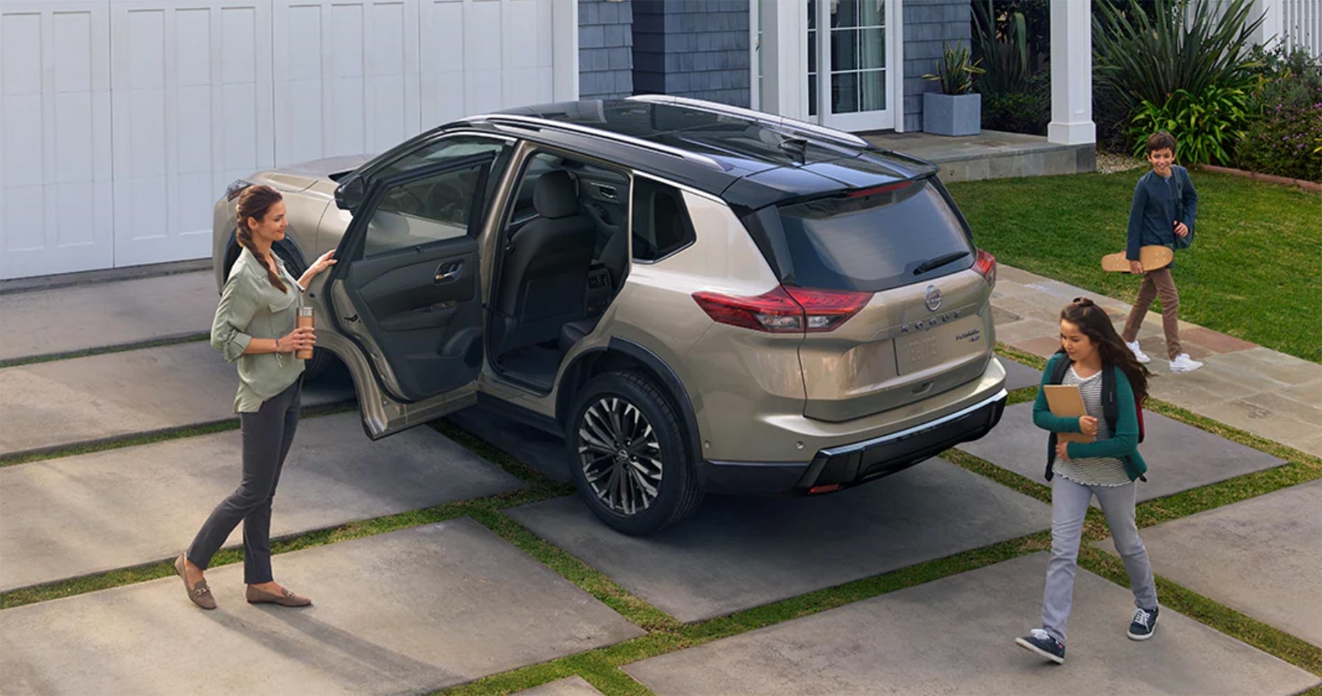 Family surrounding a 2025 Nissan Rogue parked outside a house