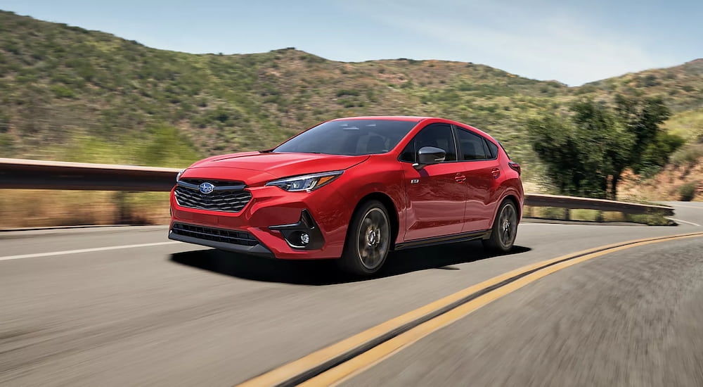 A red 2025 Subaru Impreza for sale near Poughkeepsie driving down a road.