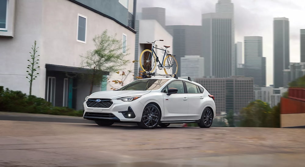 A white 2025 Subaru Impreza with a bicycle mounted to the top.