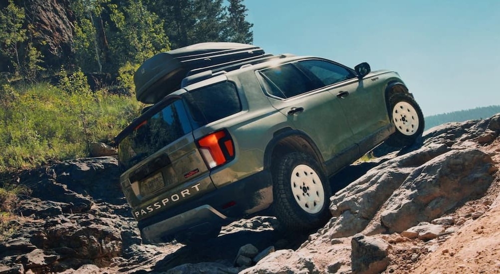 A green 2026 Honda Passport TrailSport Elite is shown off-roading.