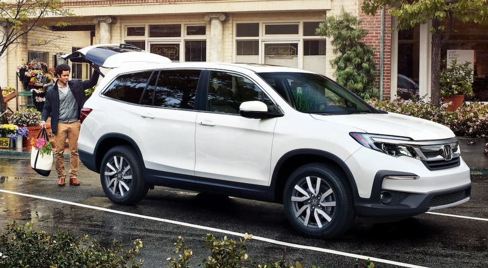 A man putting groceries into the back of a white 2020 Honda Pilot.