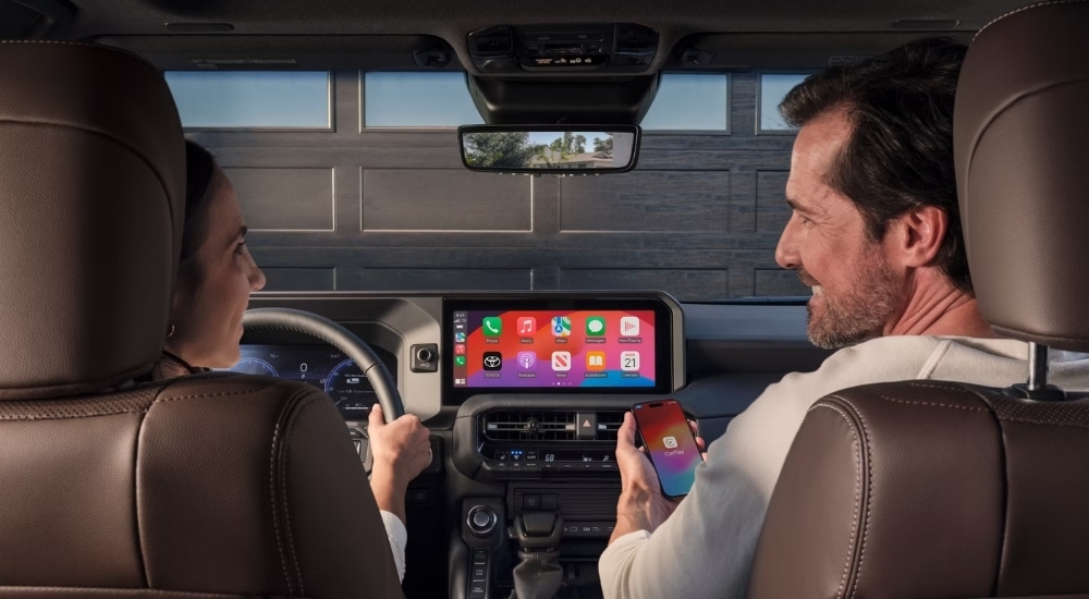 People are shown using Apple CarPlay in a 2025 Toyota Land Cruiser.