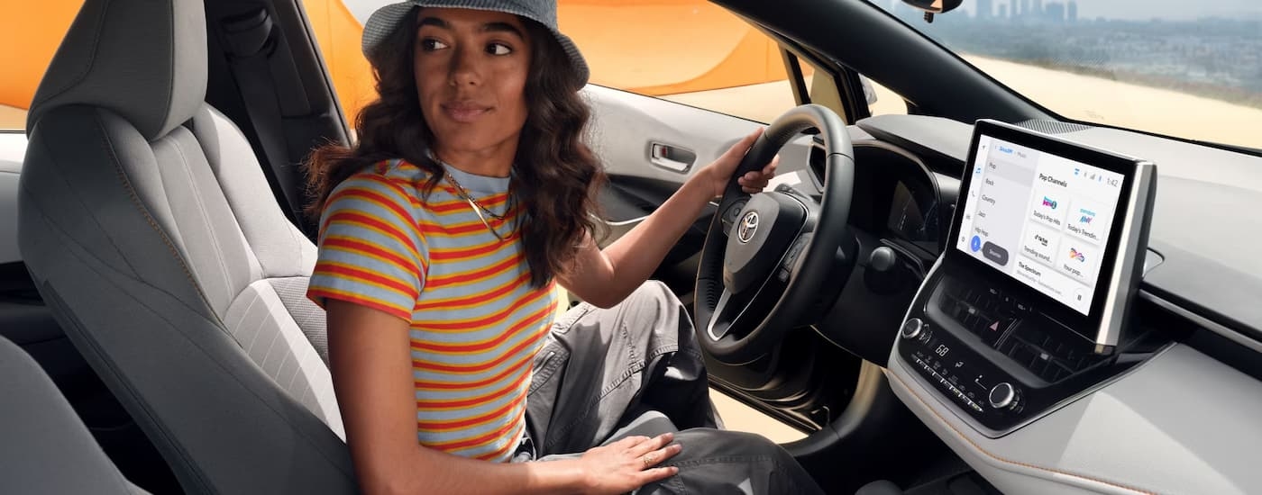 A woman is sitting in the driver's seat of a 2025 Toyota Corolla.
