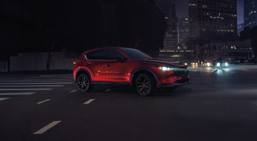 A red 2025 Mazda CX-5 is shown from the front at an angle after leaving a Mazda dealer near Tomball.