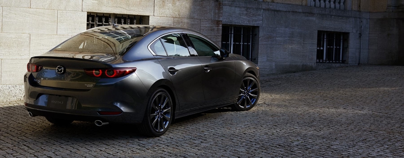 A grey 2024 Mazda3 is parked in an alleyway.