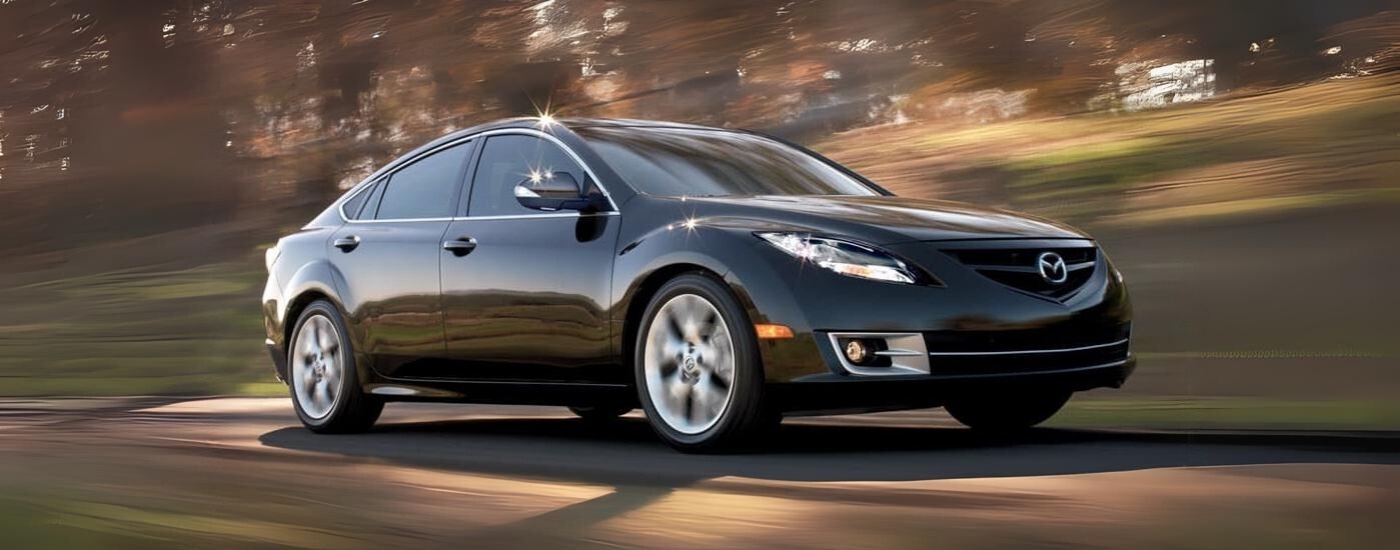 A black 2013 Mazda6 is shown from the side driving to a used Mazda dealer near Spring.