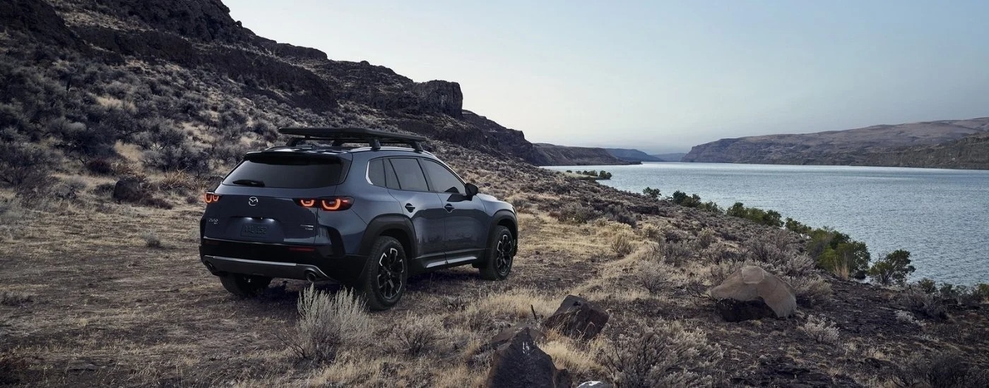A grey 2023 Mazda CX-50 is shown parked near a lake.