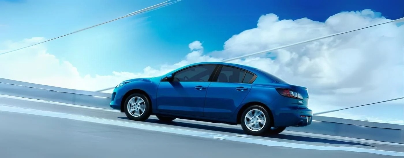 A blue 2012 Mazda3 is shown from the side driving to a Mazda dealer near Porter.