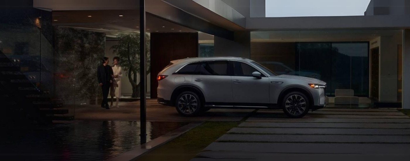 A white 2025 Mazda CX-90 PHEV for sale is shown from the side at night.