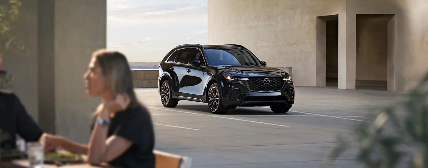 A red 2019 Mazda CX-3 is shown from the side parked in front of a shop.
