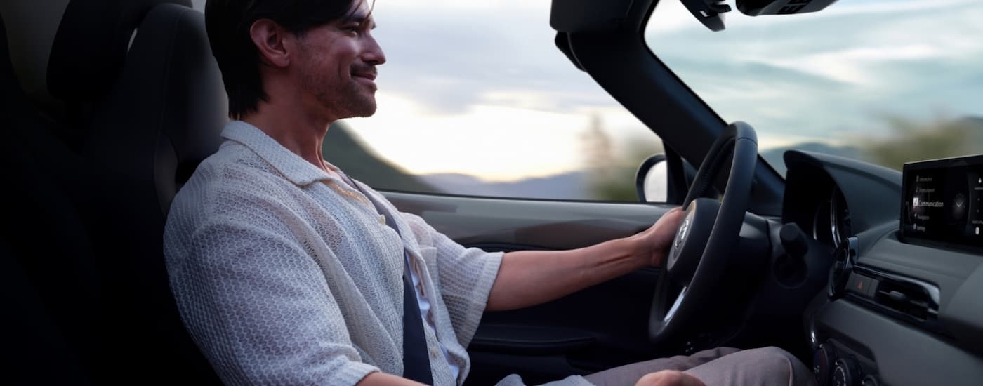 Man driving a 2025 Mazda MX-5 Miata on a sunny day.