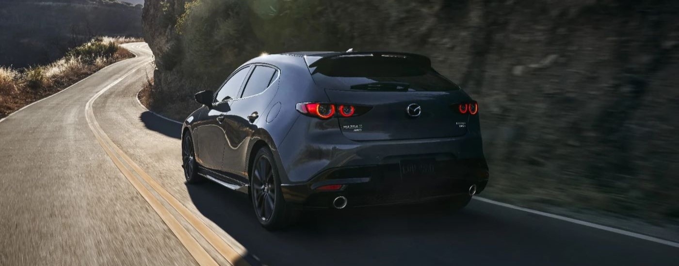 A grey 2022 Mazda 3 Hatchback driving on a winding road.