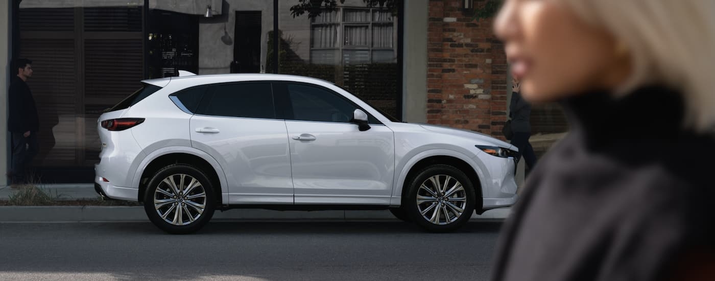 A woman walking past a white 2023 Mazda CX-5.
