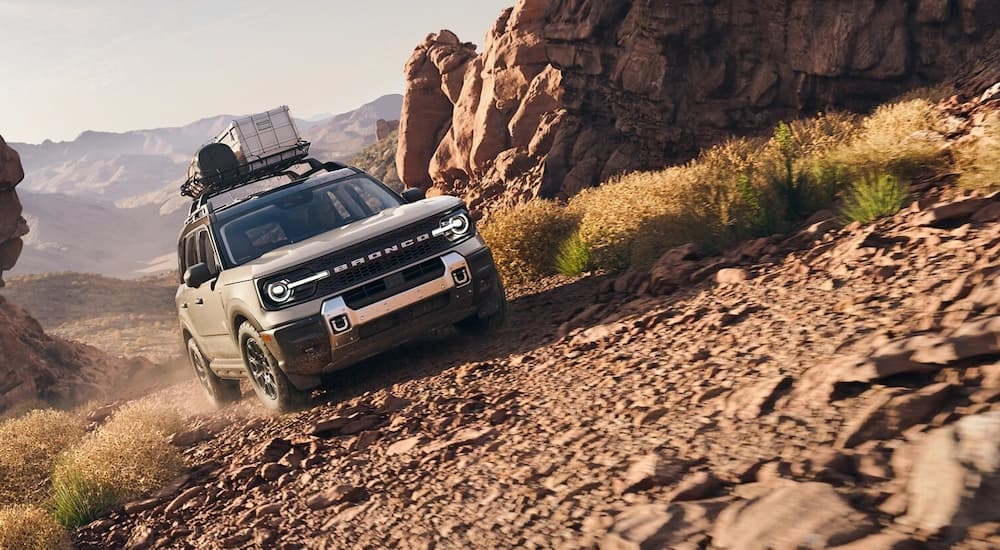 A white 2025 Ford Bronco Sport driving off-road up a hill.