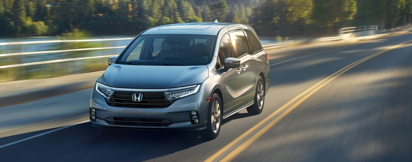 A grey 2024 Honda Odyssey Elite is driving to look at a used Honda for sale.