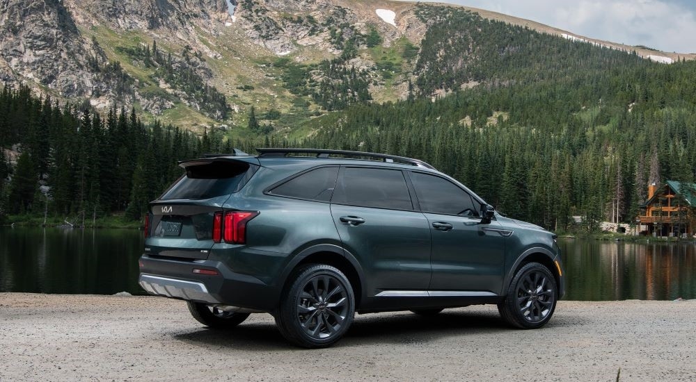 Rear view of a dark green 2025 Kia Sorento parked near a lake.