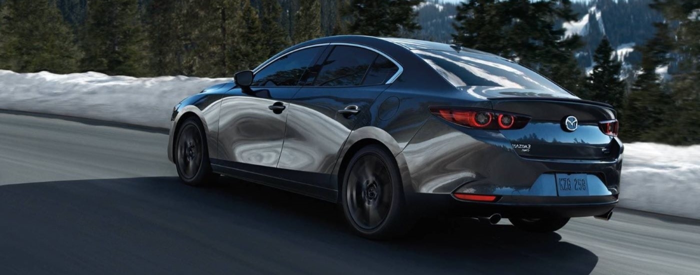 Rear view of a black 2024 Mazda3 driving from a Mazda dealer near Hialeah.
