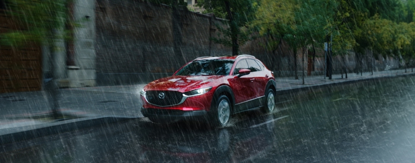 A red 2025 Mazda CX-30 for sale driving in the rain.