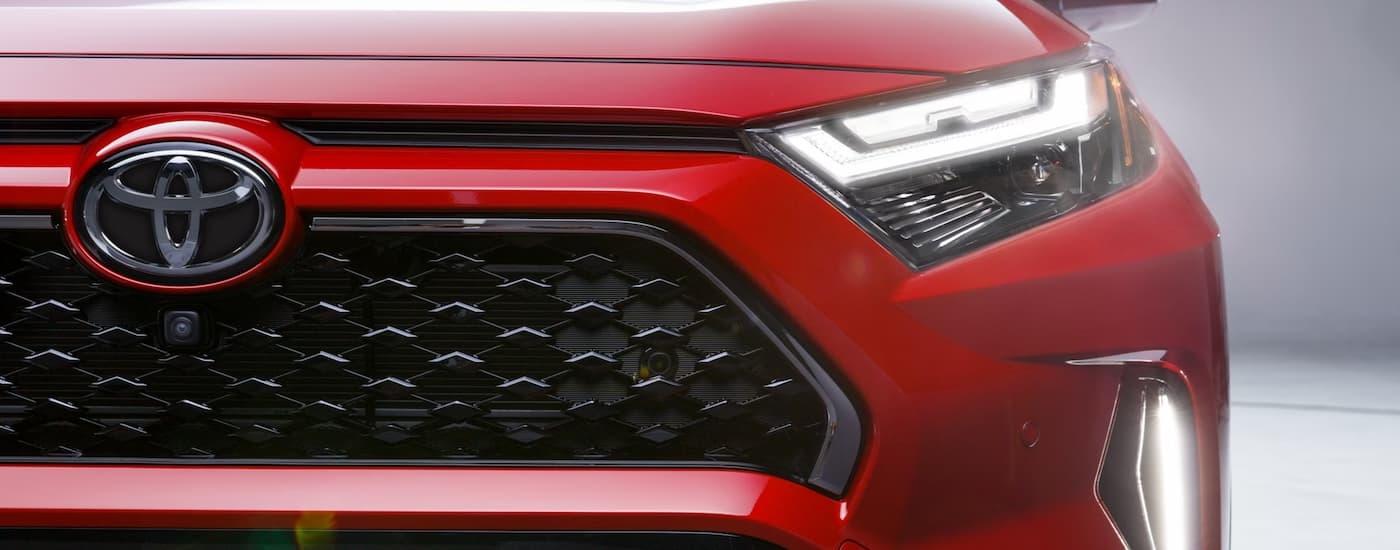 A close-up on the grille of a red 2025 Toyota RAV4 PHEV.