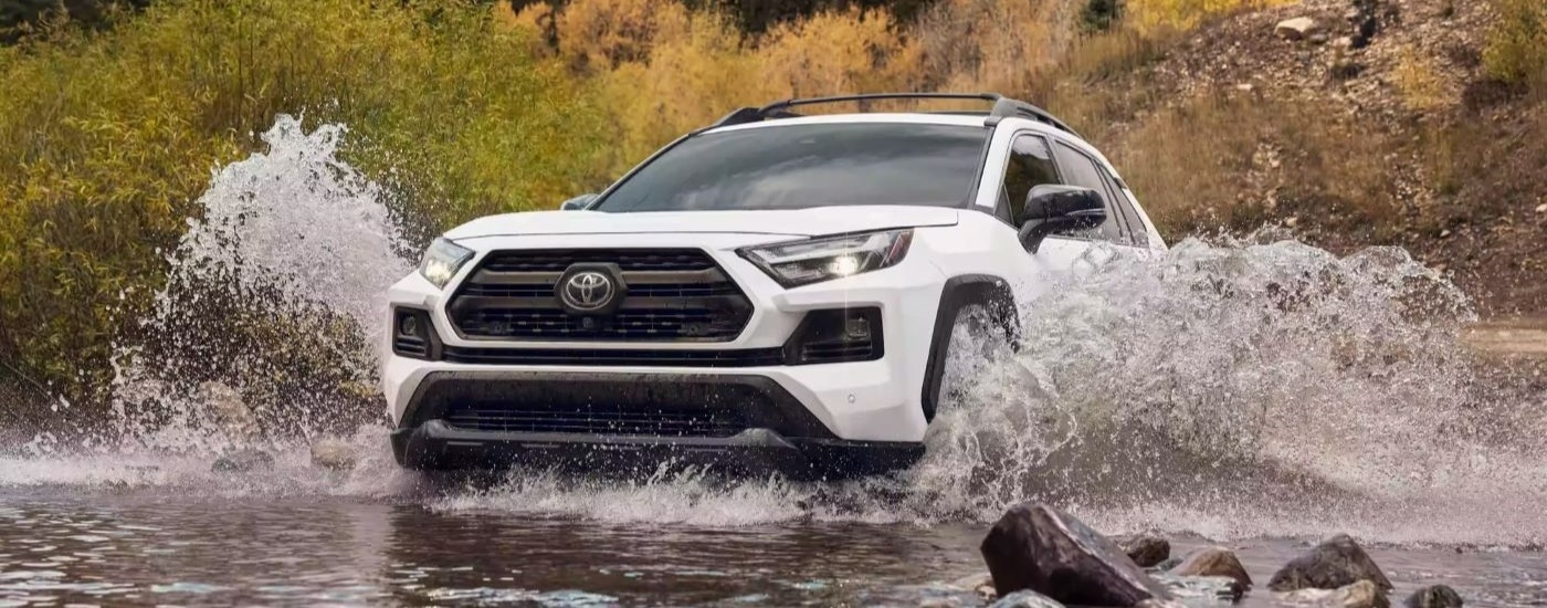 A white 2023 Toyota RAV4 TRD driving over a shallow river.