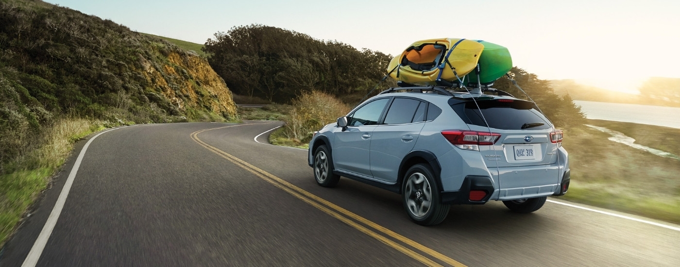 A blue 2020 Subaru Crosstrek Limited driving past a lake.