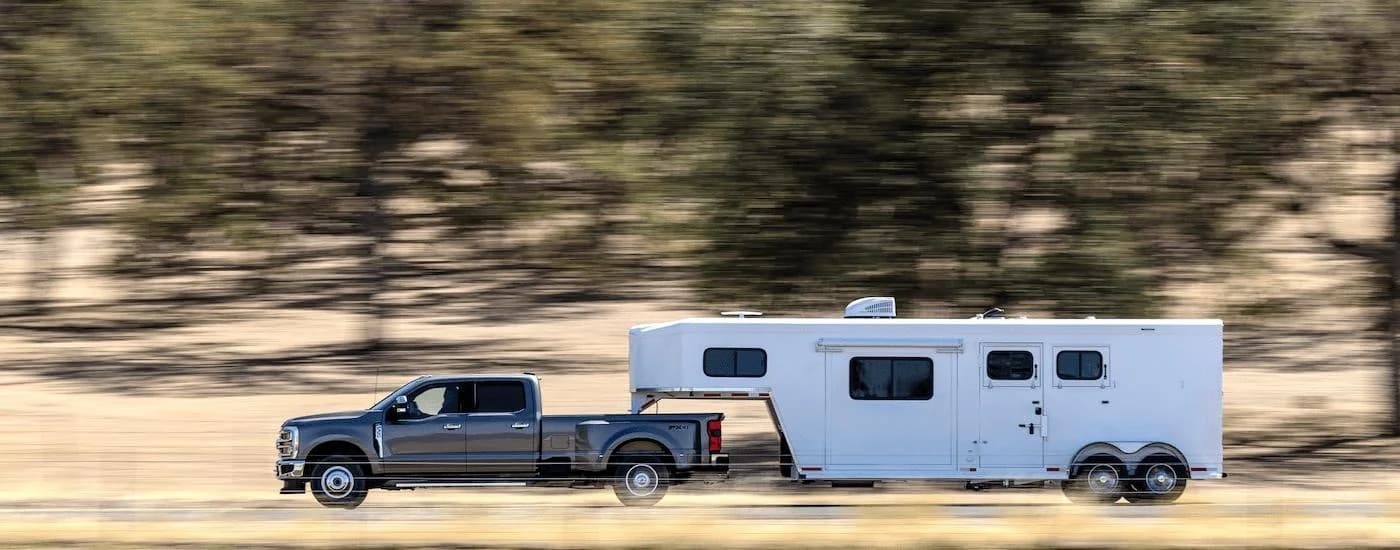 A grey 2025 Ford F-350 from the side while towing.