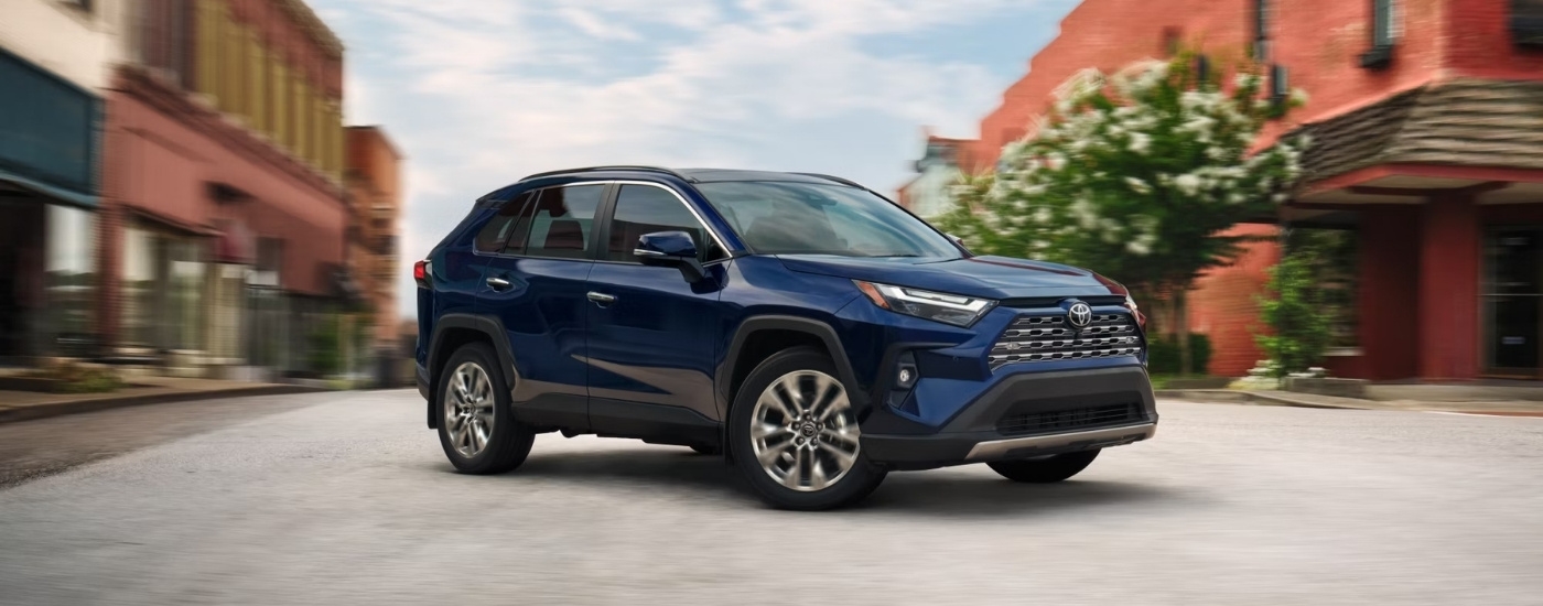 A dark 2025 blue Toyota RAV4 for sale near Bennington driving through an intersection.