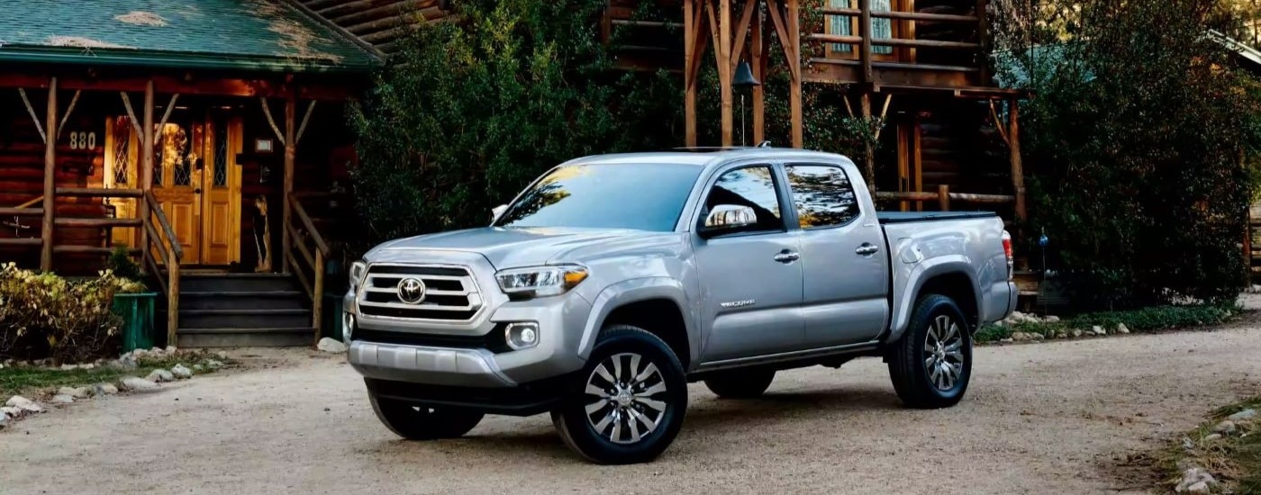 Silver 2022 Toyota Tacoma parked outside of a log cabin.