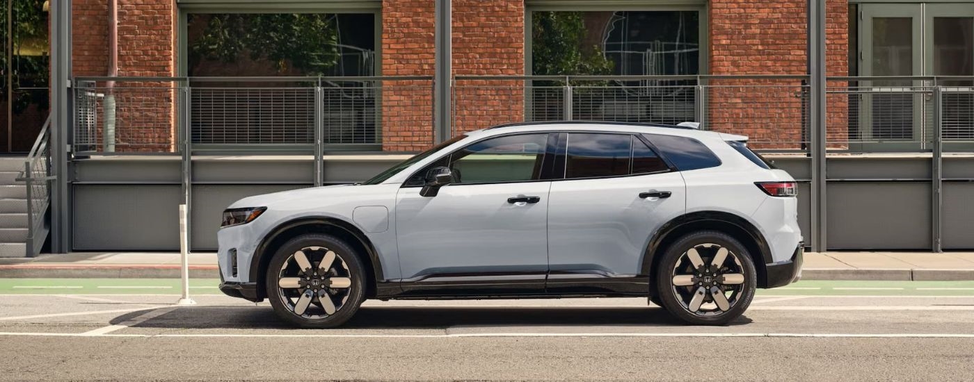 A white 2025 Honda Prologue Elite in front of a brick building.