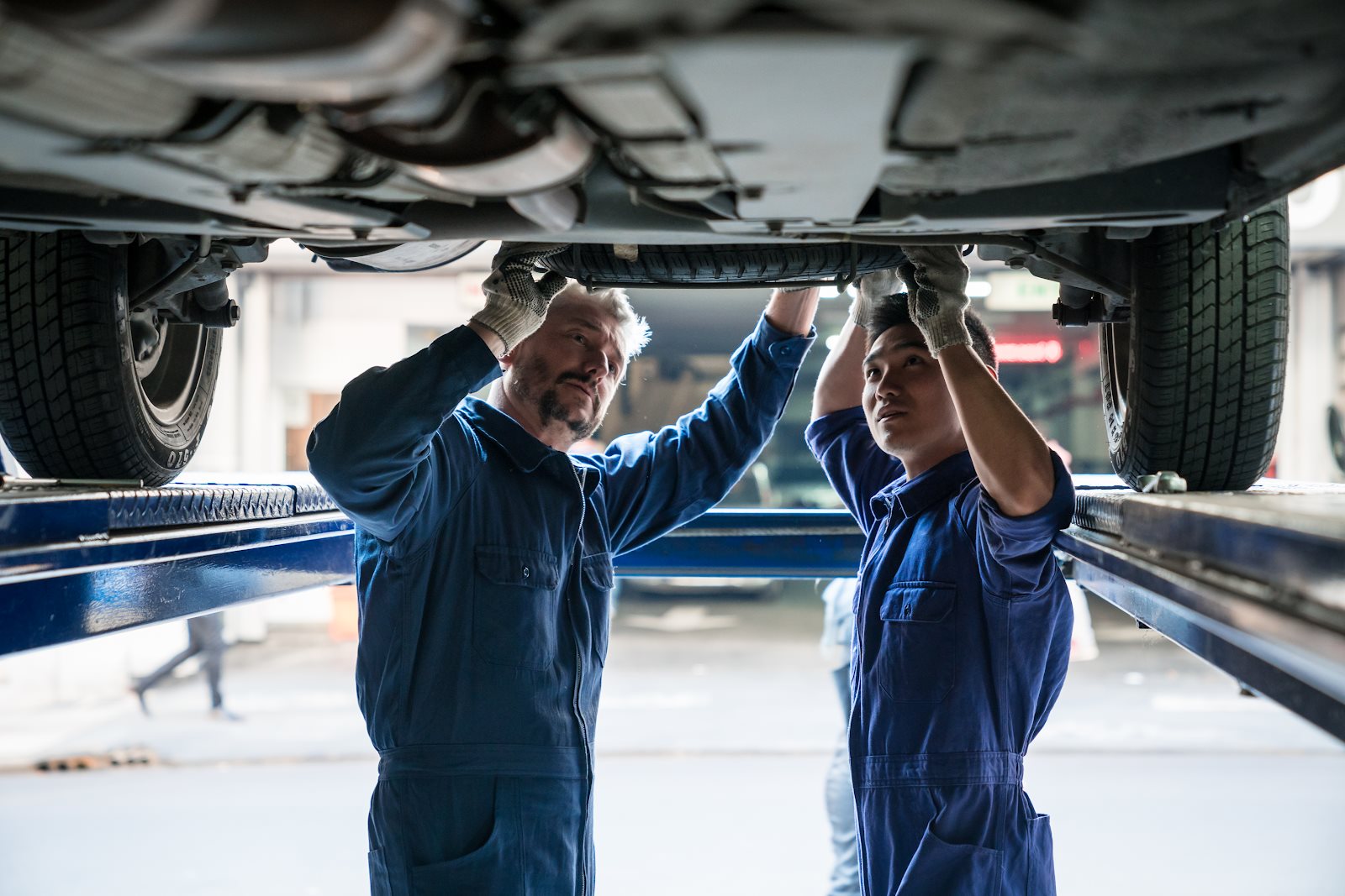 Technicians servicing a vehicle on a lift