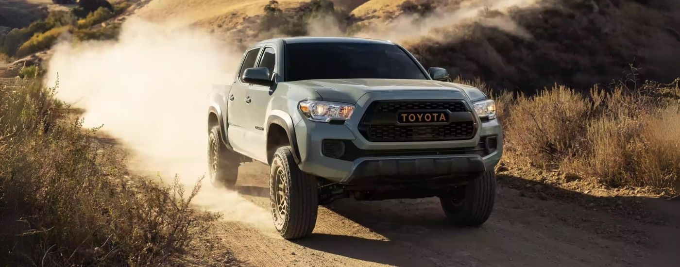 A grey 2023 Toyota Tacoma SR5 Trail Edition for sale near Franklin driving down a dirt road.