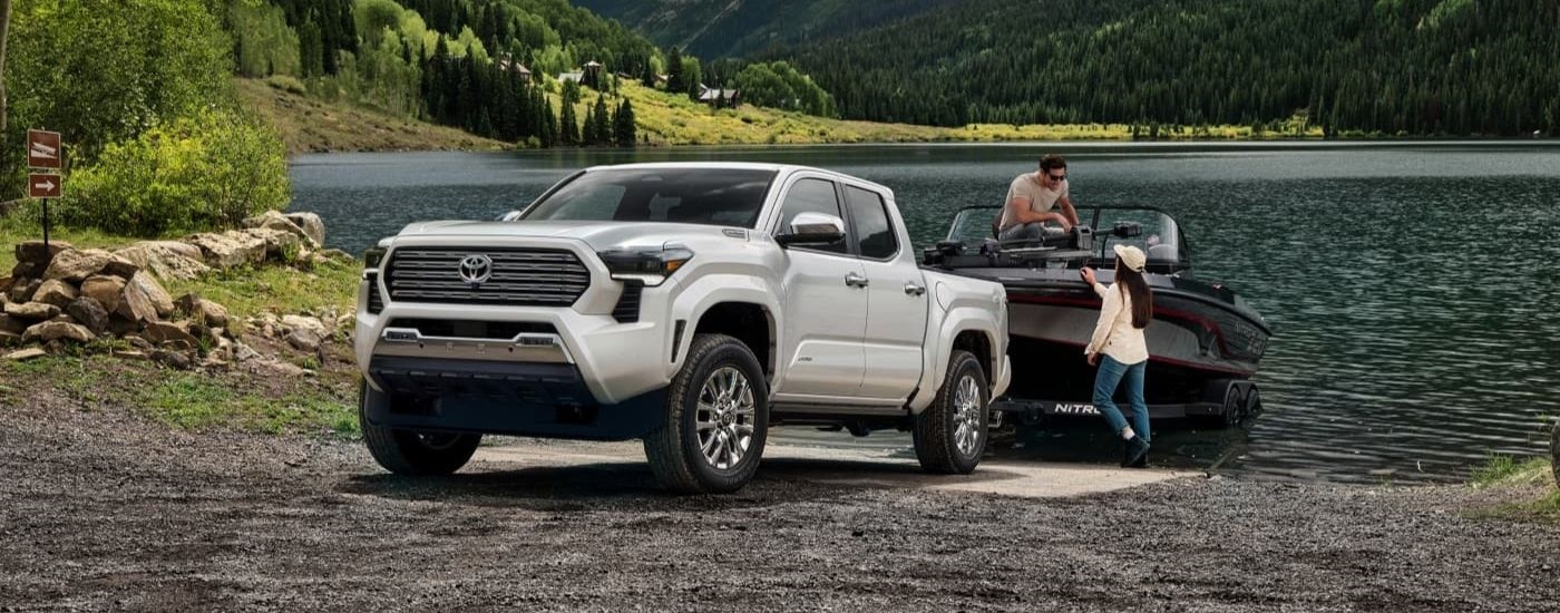 A white 2024 Toyota Tacoma Limited towing a boat out of a lake.