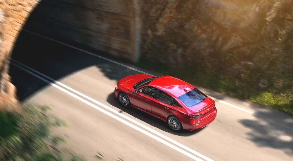 Red 2023 Honda Civic driving under a tunnel.