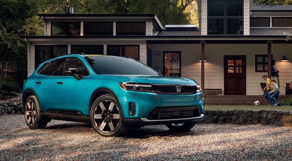 A blue 2025 Honda Prologue parked in front of a house.