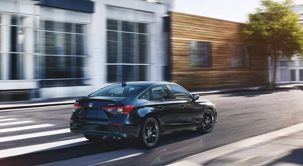 Black 2024 Honda Civic driving on a city street.