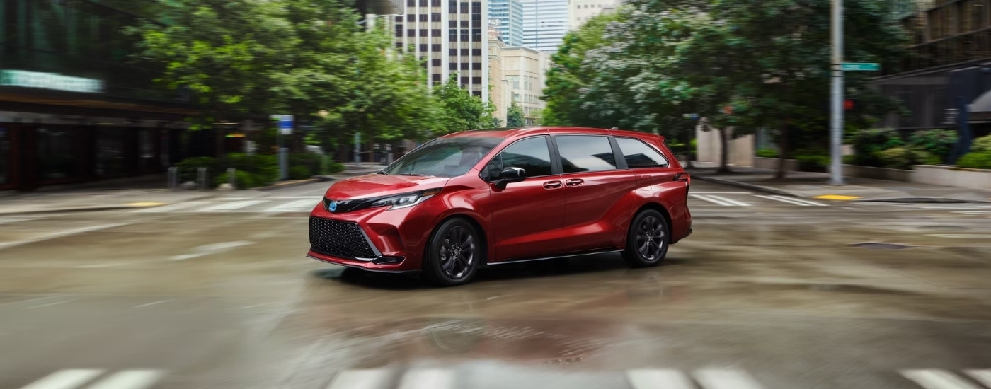 A red 2025 Toyota Sienna XSE driving through an intersection.