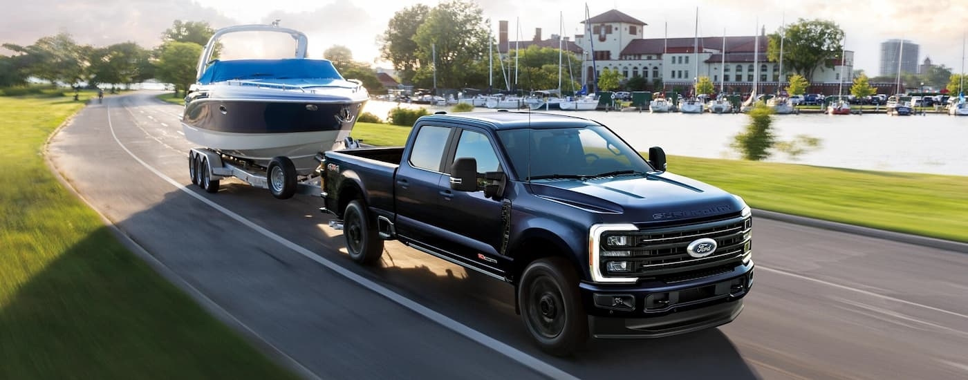 A black 2025 Ford F-350 for sale near Saugerties towing a boat down an open road.