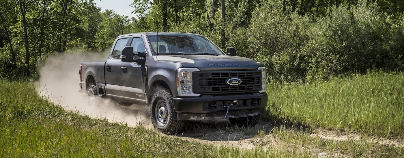 A grey 2025 Ford F-350 for sale near Kingston driving down a trail.