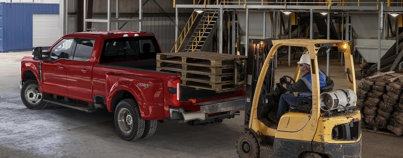 Rear view of a red 2025 Ford F-350 transporting pallets in a warehouse.