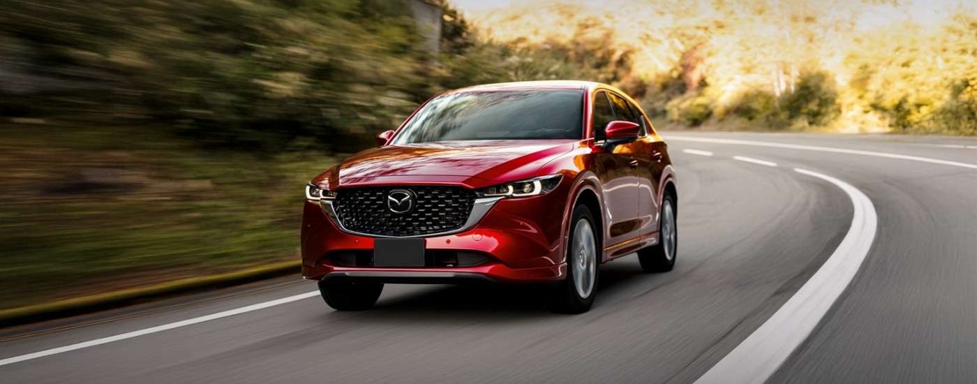 A red 2025 Mazda CX-5 for sale rounding a corner.