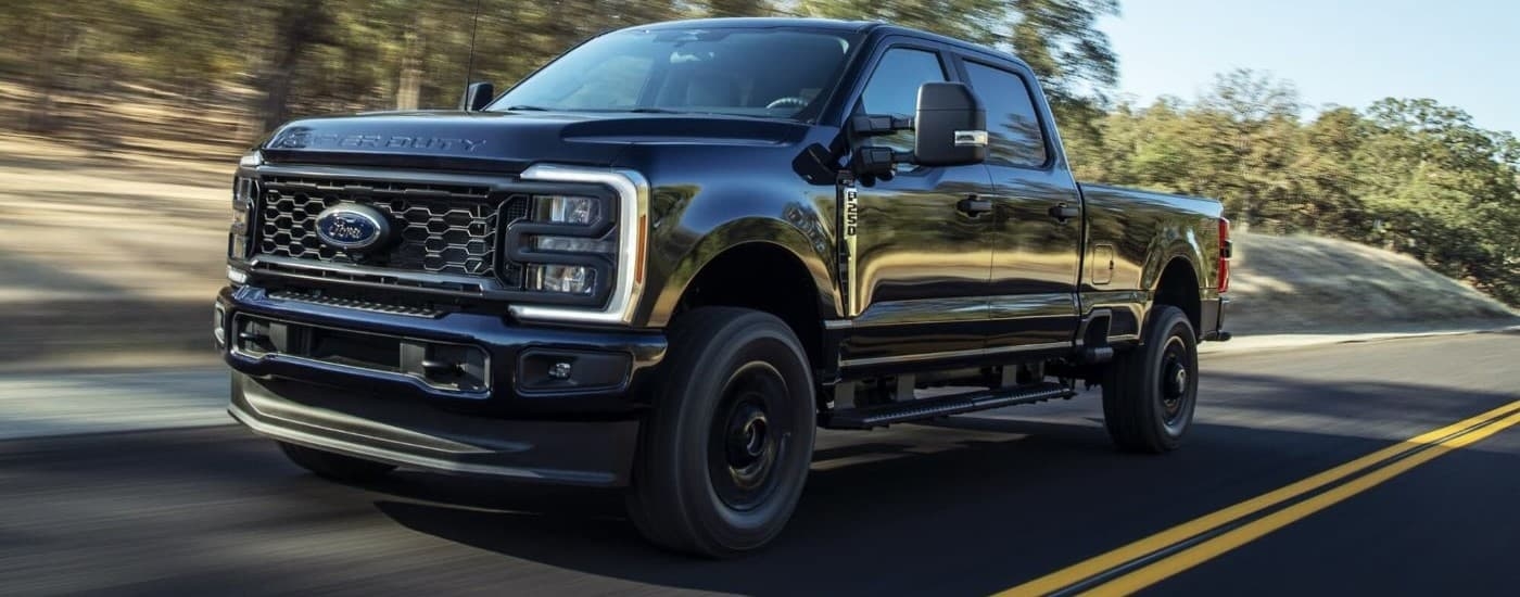 Black 2024 Ford F-250 XL STX driving down an open road.