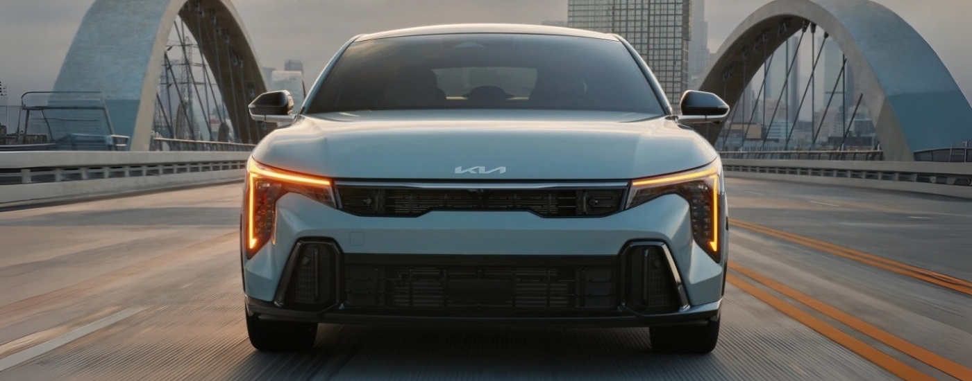 A silver 2025 Kia K4 for sale near Houston driving over a bridge.