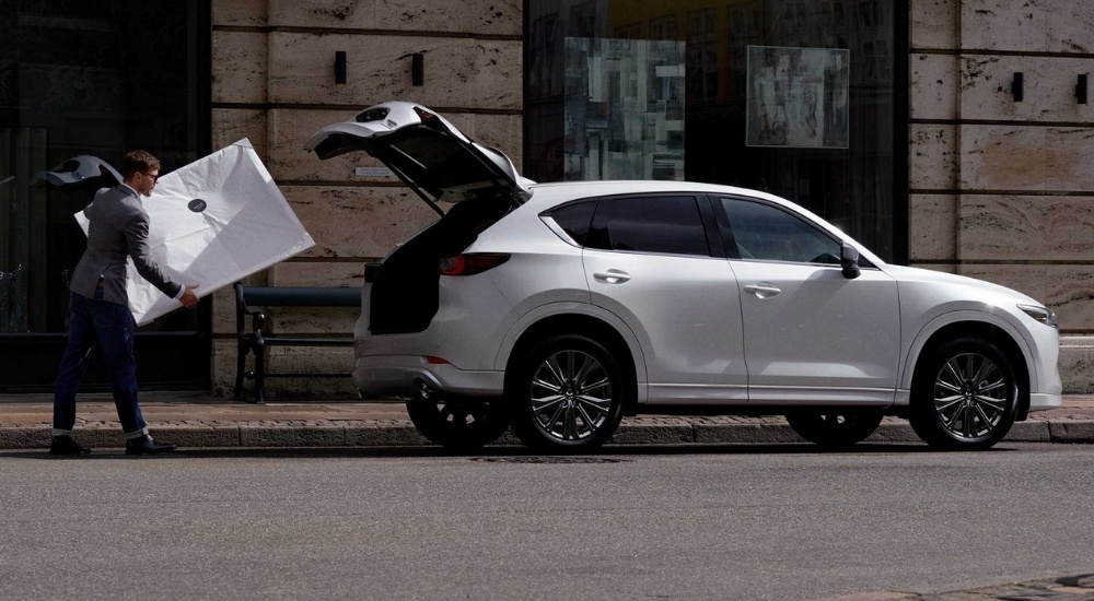 A person loading a painting into the trunk of a 2025 Mazda CX-5.