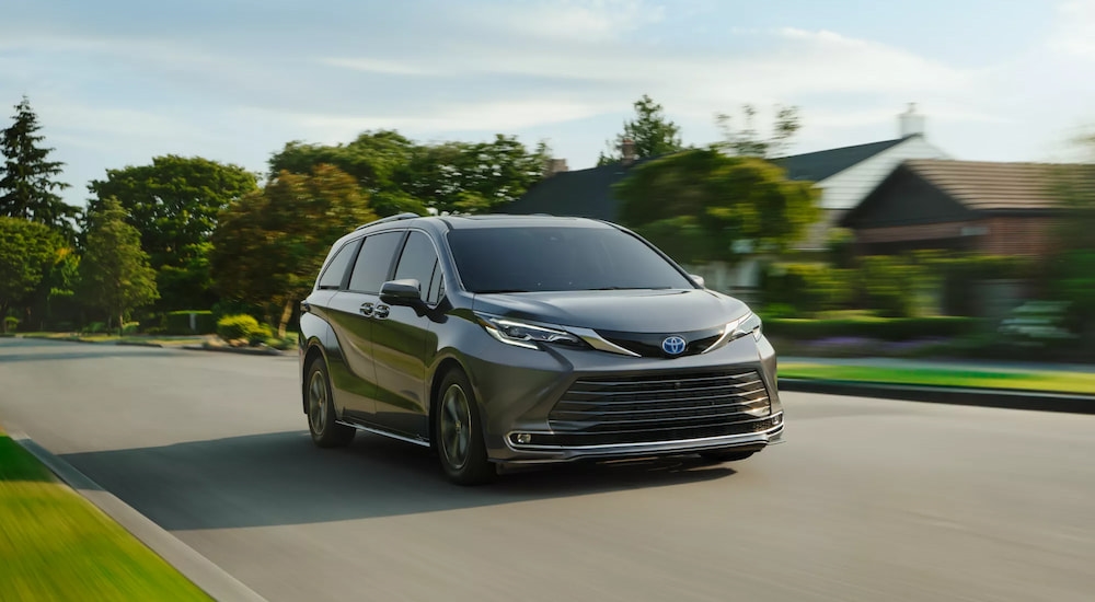 Grey 2025 Toyota Sienna driving down a neighborhood road.